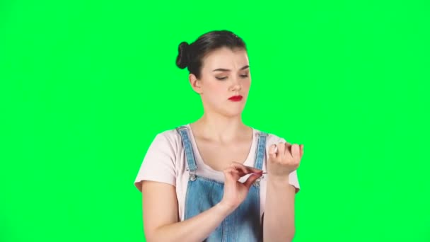 Girl with two hair-buns and red lips makes herself manicure with pink nail file, slow motion — 图库视频影像