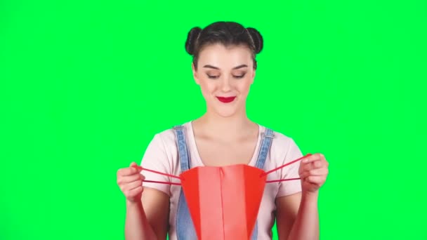 Girl takes out package then looks into it and is very upset on a green screen, slow motion — 图库视频影像