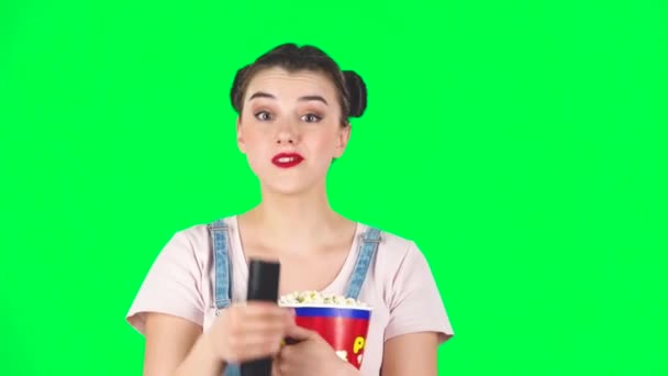 Vrouw kauwt popcorn en wisselt van kanaal met TV afstandsbediening. Groen scherm, slow motion — Stockvideo