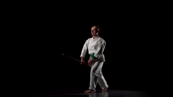 Kendo μαχητής σε λευκό κιμονό εξάσκηση πολεμικές τέχνες με το μπαμπού bokken σε μαύρο φόντο. — Αρχείο Βίντεο