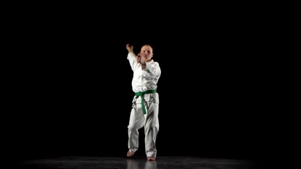 Kendo fighter na białym kimono ćwiczenia sztuki walki z bambusa bokken na czarnym tle. — Wideo stockowe
