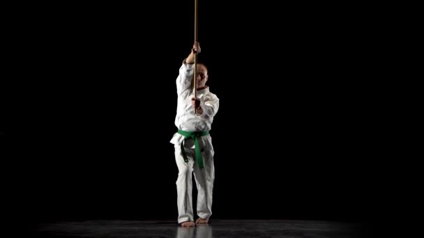 Kendo bojovník na bílém kimonu cvičí bojové umění s bambusovým bokken na černém pozadí. — Stock video