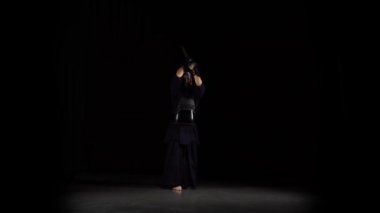 Güçlü Kendo gurusu, siyah arka planda bambu bokken ile dövüş sanatları yapıyor..