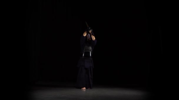 Starker Kendo-Guru, der Kampfkunst mit dem Bambusbokken auf schwarzem Hintergrund praktiziert. — Stockvideo