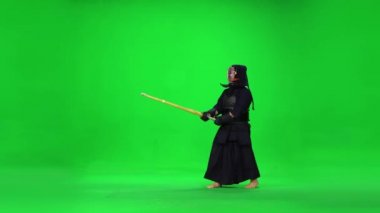 Maskülen Kendo savaşçısı yeşil ekranda bambu bokken ile dövüş sanatları yapıyor..