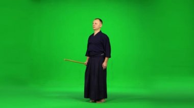 Maskülen Kendo savaşçısı yeşil ekranda bambu bokken ile dövüş sanatları yapıyor..