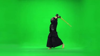 Maskülen Kendo savaşçısı yeşil ekranda bambu bokken ile dövüş sanatları yapıyor..