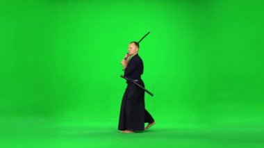Maskülen Kendo savaşçısı yeşil ekranda bambu bokken ile dövüş sanatları yapıyor..