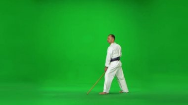 Erkek Kendo ustası beyaz kimono savaşçısı bambu bokken ile yeşil ekranda dövüş sanatları yapıyor..