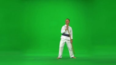 Erkek Kendo ustası beyaz kimono savaşçısı bambu bokken ile yeşil ekranda dövüş sanatları yapıyor..