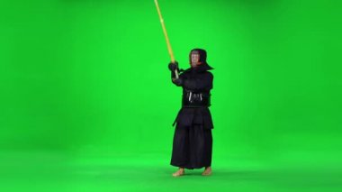 Maskülen Kendo savaşçısı yeşil ekranda bambu bokken ile dövüş sanatları yapıyor..