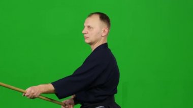 Erkek Kendo savaşçısı, yeşil ekranda bambu bokken ile dövüş sanatları yapıyor. Kapat.