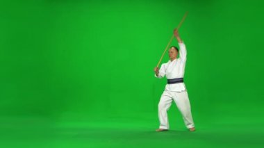 Erkek Kendo ustası beyaz kimono savaşçısı bambu bokken ile yeşil ekranda dövüş sanatları yapıyor..