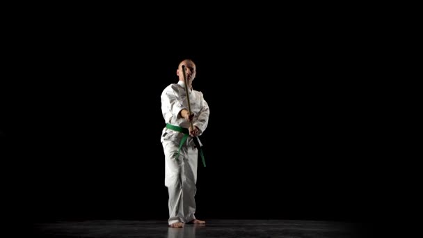 Kendo combattente su kimono bianco praticare arte marziale con il bokken di bambù su sfondo nero . — Video Stock