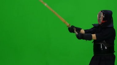 Erkek Kendo savaşçısı, yeşil ekranda bambu bokken ile dövüş sanatları yapıyor. Kapat.