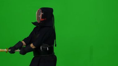 Erkek Kendo savaşçısı, yeşil ekranda bambu bokken ile dövüş sanatları yapıyor. Kapat.