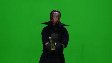 Erkek Kendo savaşçısı, yeşil ekranda bambu bokken ile dövüş sanatları yapıyor. Kapat.