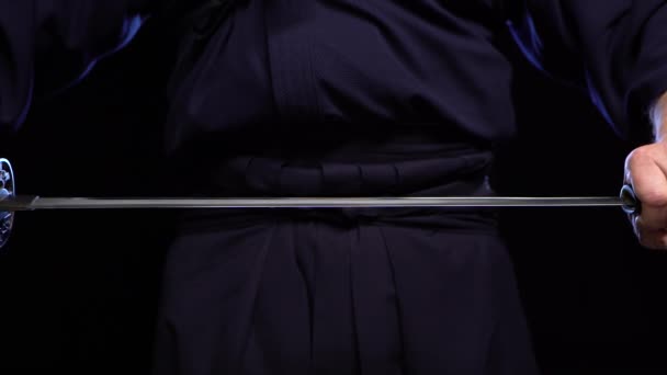 Een close-up shot van een ninja mannenhand die een zwaard vasthoudt en het optilt. — Stockvideo