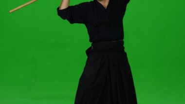 Erkek Kendo savaşçısı, yeşil ekranda bambu bokken ile dövüş sanatları yapıyor. Kapat.