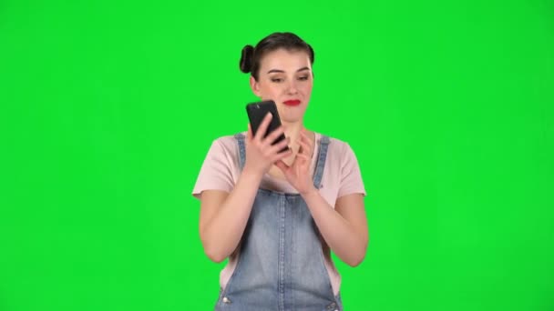 Porträtt av leende flicka talar för mobiltelefon och glädjas på grön skärm — Stockvideo