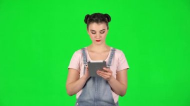 Genç gülümseyen kadın yeşil ekranda tablet bilgisayarında mesaj atıyor.