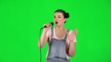 Neşeli kız mikrofona şarkı söyler ve müziğin ritmine göre hareket eder.