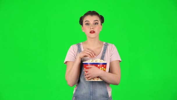 Солодка дівчина жує попкорн під час перегляду фільму. Дівчина дивиться з закляттям і сміється — стокове відео