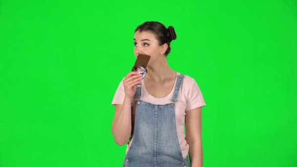 Το κορίτσι κρατάει σοκολάτα και ένα μήλο στα χέρια της, διαλέγοντας ανάμεσα τους. — Αρχείο Βίντεο