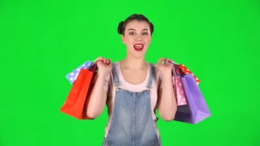 Farklı renkte alışveriş paketleri olan kız yeşil ekranda neşeyle dans ediyor.