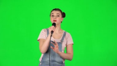 Çekici kız mikrofona şarkı söyler ve müziğin ritmine göre hareket eder.