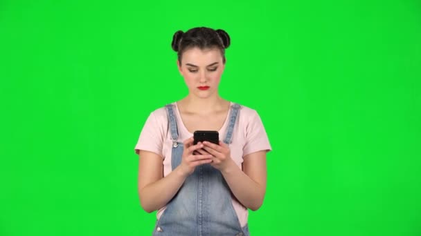 Дівчина сердито пише на своєму телефоні на зеленому екрані — стокове відео