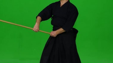 Erkek Kendo savaşçısı, yeşil ekranda bambu bokken ile dövüş sanatları yapıyor. Kapat.