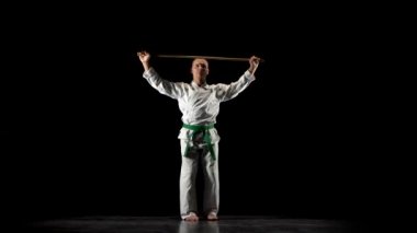 Beyaz kimonolu Kendo dövüşçüsü siyah arka planda bambu bokken ile dövüş sanatları yapıyor..