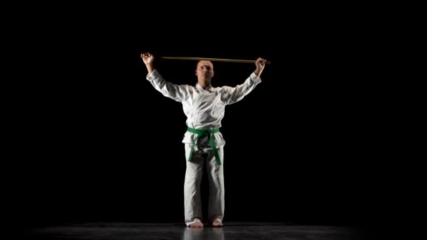 Luchador Kendo en kimono blanco practicando arte marcial con el bokken de bambú sobre fondo negro . — Vídeo de stock