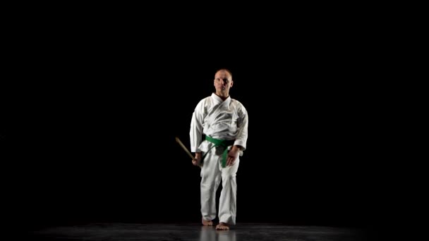 Боец Кендо на белом кимоно практикующий боевое искусство с бамбуковым боккеном на черном фоне . — стоковое видео