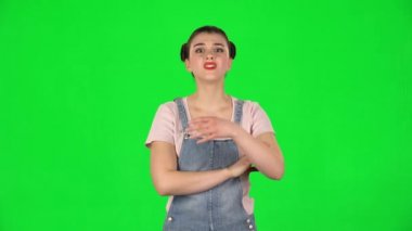 Kız kameraya bakarak bilgi dinliyor, şok olmuş ve yeşil ekranda çok üzgün.