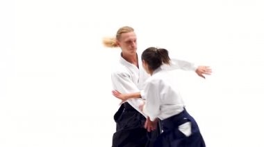 Beyaz keikogi giymiş erkek ve kadın aikido teknikleri gösteriyor, beyazdan izole edilmiş. Kapat..