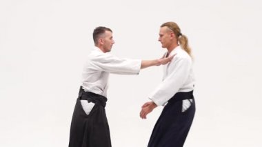 Kimonolu iki adam aikido teknikleri uyguluyor, beyazlar üzerinde izole edilmiş. Kapatın. Yavaş çekim.