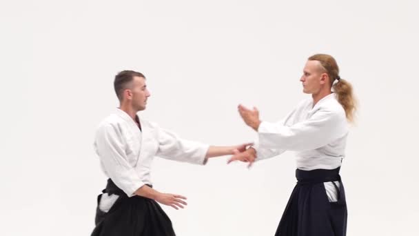 Dois caras em quimono demonstrando técnicas de aikido, isolados em branco. Fecha. Movimento lento . — Vídeo de Stock