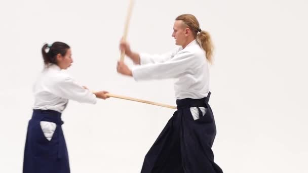 Man och kvinna övar aikido med bokken. Isolerad på vitt. Närbild. Långsamma rörelser. — Stockvideo