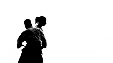 Aikido teknikleri gösteren siyah siluetler. Beyazda izole edilmiş. Ağır çekim. Kapat..