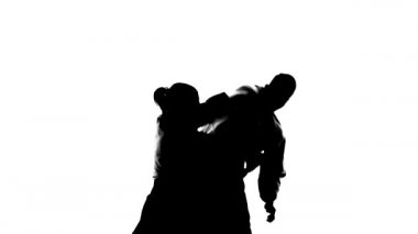 Aikido teknikleri gösteren siyah siluetler. Beyazda izole edilmiş. Ağır çekim. Kapat..
