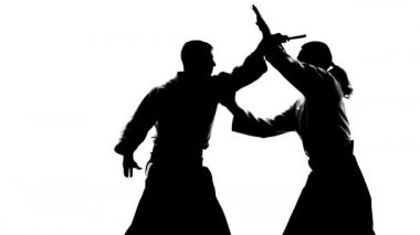 Keikogi ya da kimonolu iki erkeğin siyah siluetleri aikido yaparken tanto kullandıklarını gösteriyor. İzole edilmiş, beyaz. Ağır çekim. Kapat..