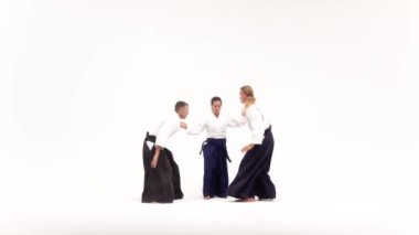 İki erkek ve kadın aikido teknikleri uyguluyor, beyazlar üzerinde izole edilmiş. Yavaş çekim.