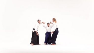 İki erkek ve kadın aikido teknikleri uyguluyor, beyazlar üzerinde izole edilmiş. Yavaş çekim.