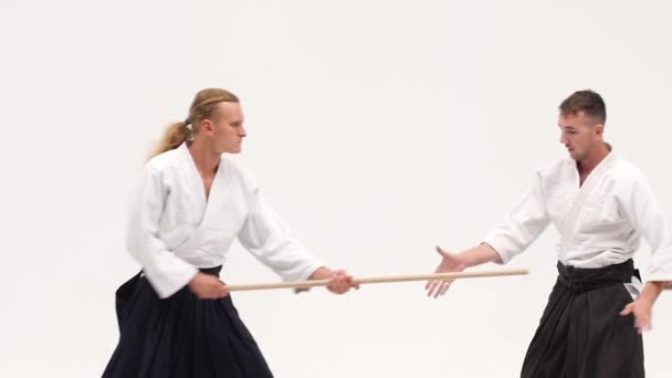 Δύο αθλητές που εκτελούν aikido χρησιμοποιώντας bokken. Απομονωμένος, λευκός. Κλείσε. Αργή κίνηση. — Αρχείο Βίντεο