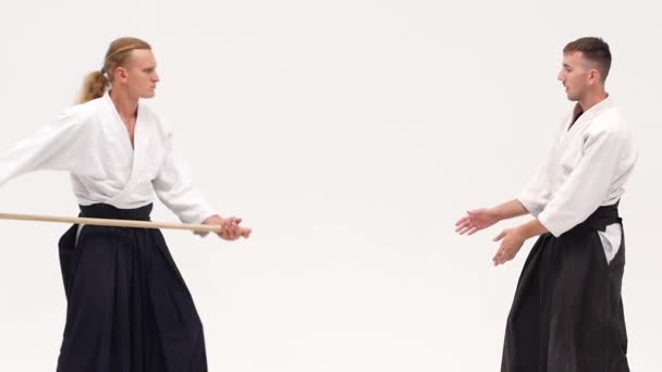 Två idrottare som utför aikido med bokken. Isolerad, vit. Närbild. Långsamma rörelser. — Stockvideo