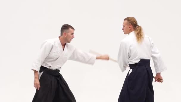 Deux athlètes exécutant l'aikido en utilisant bokken. Isolé, blanc. Ferme là. Mouvement lent . — Video