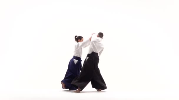 Muž a žena v bílém keikogi ukazující techniky aikida, izolovaní na bílém. Zpomalený pohyb. — Stock video