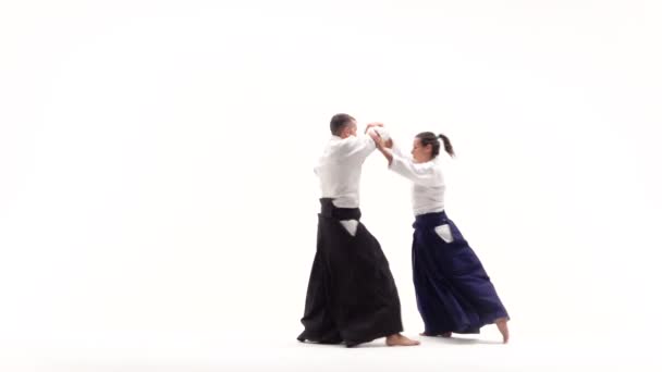 Man en vrouw in witte keikogi met aikido technieken, geïsoleerd op wit. Langzame beweging. — Stockvideo